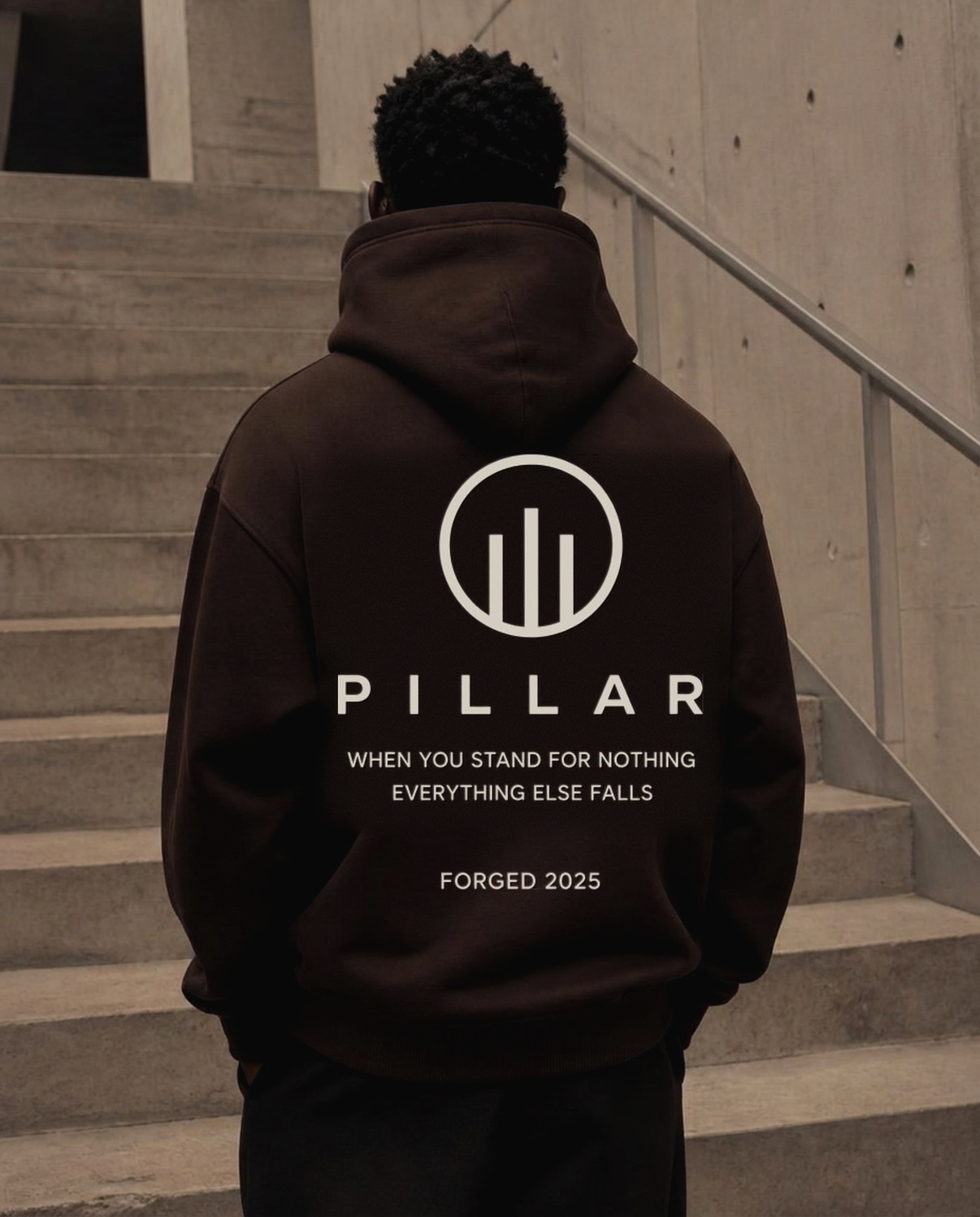 Standing Black male model showing the back of the brown PILLAR Forged Hoodie