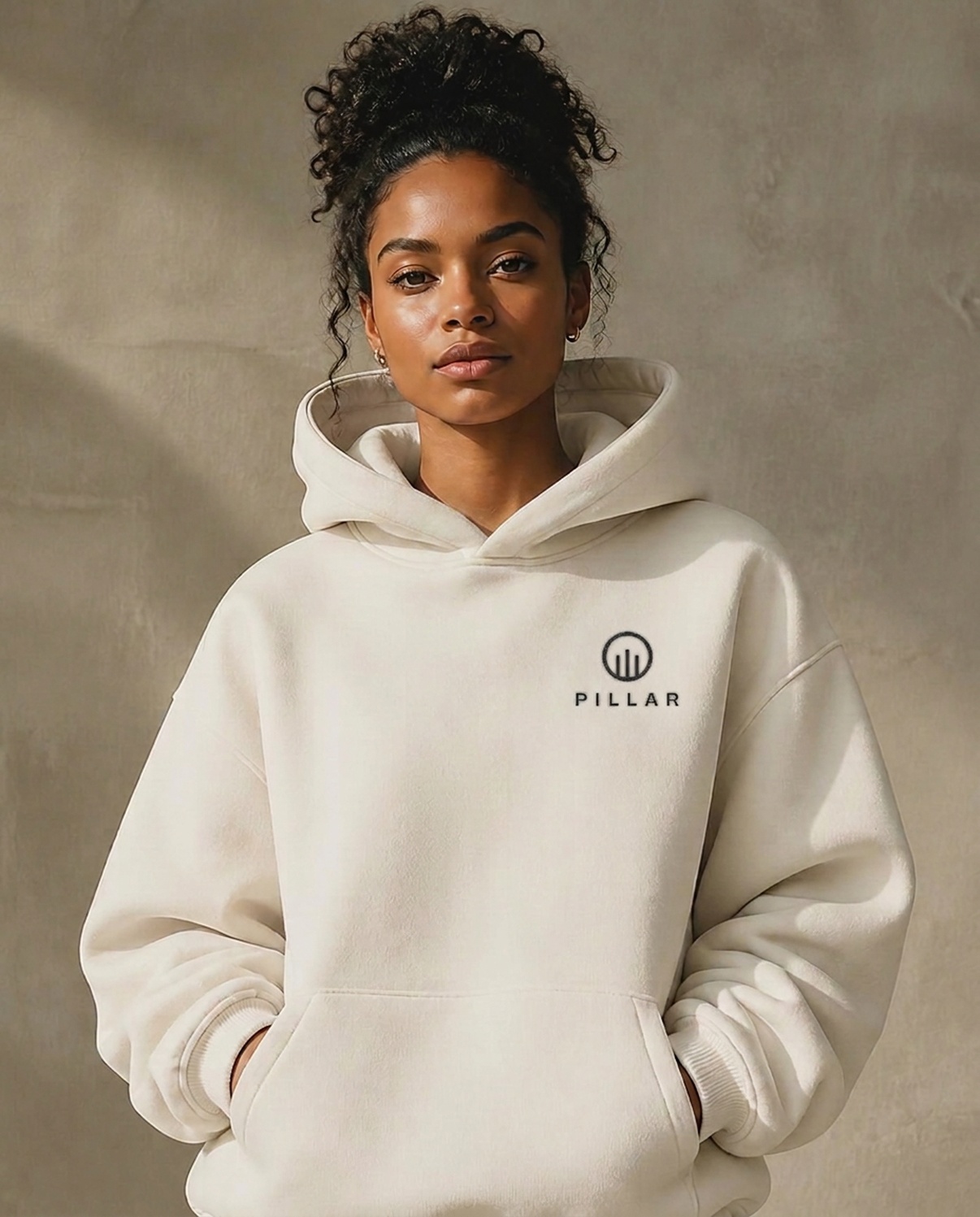 Black female model wearing the off-white PILLAR Forged Hoodie with the embroidered left-chest lockup